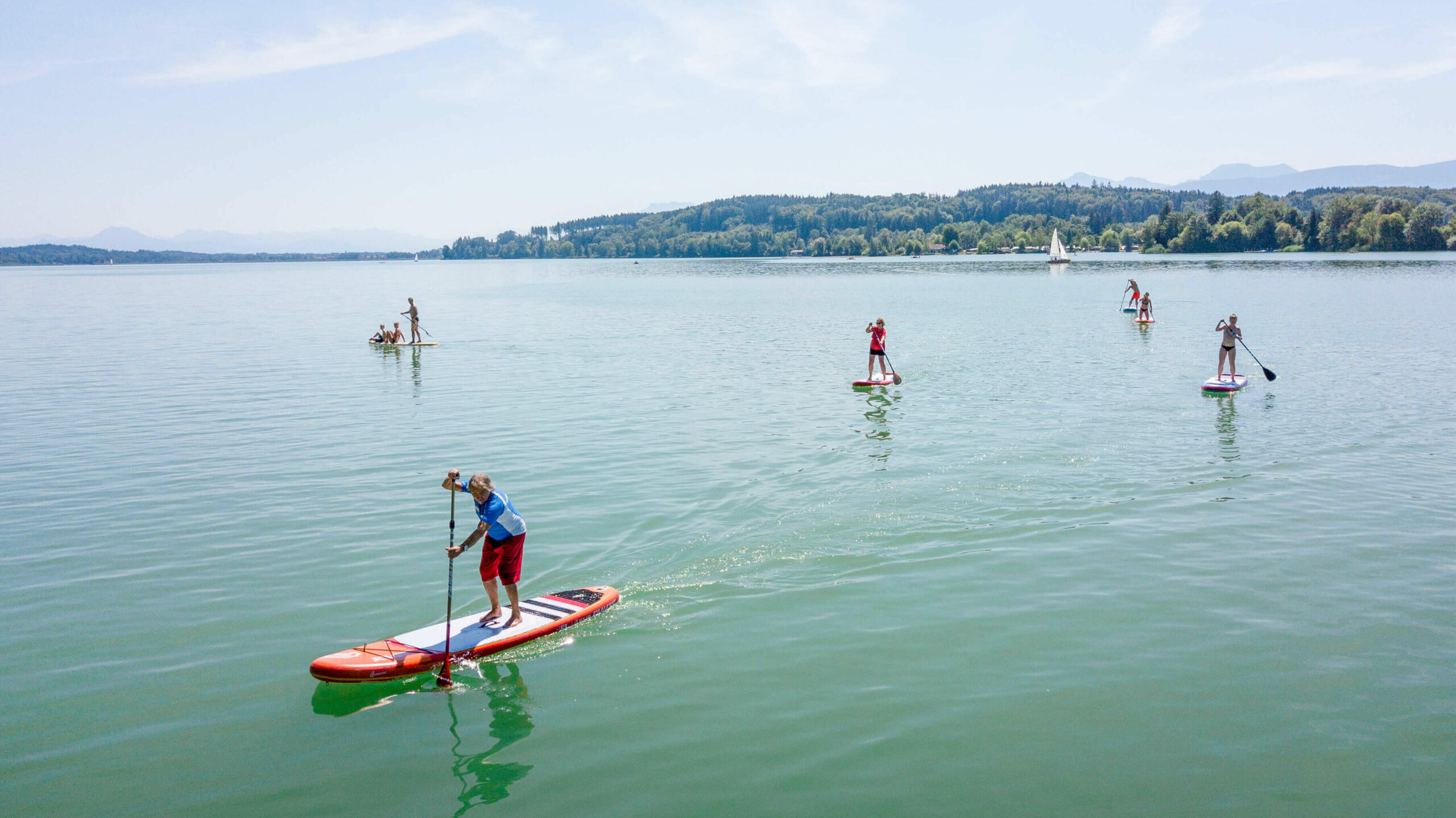 mehrere Stand-up-Paddler, die auf dem Waginger See fahren