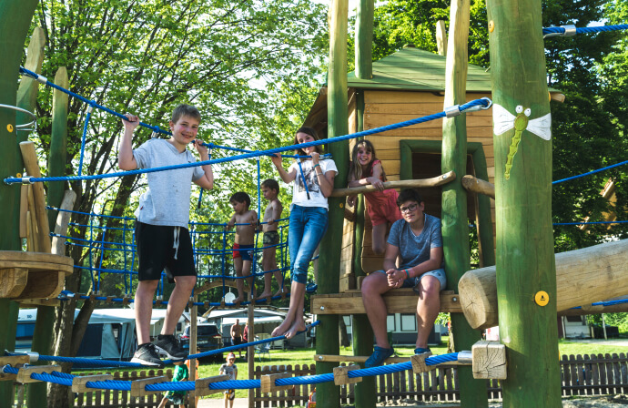 Kinder spielen auf einem Spielplatz mit vielen Hängebrücken und Klettermöglichkeiten