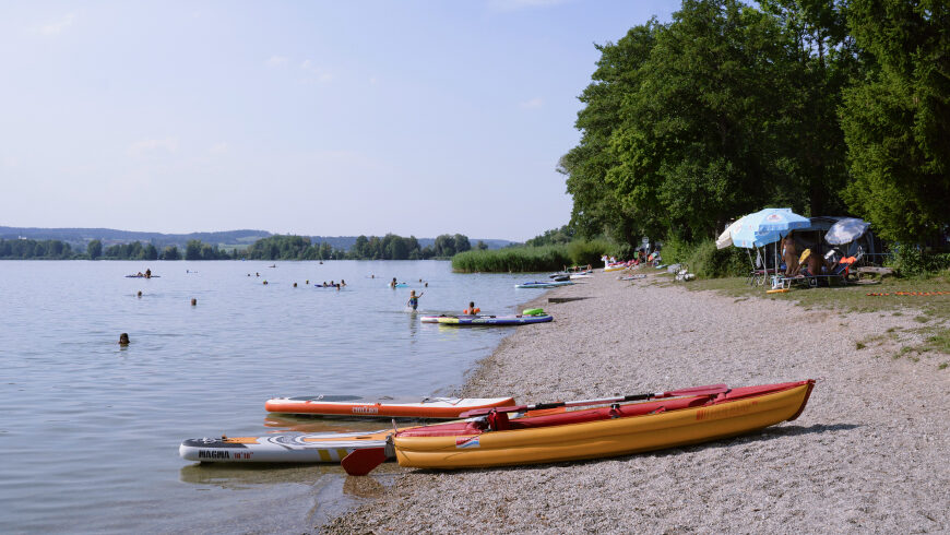 Am Badestrand des Sees baden mehrere Personen