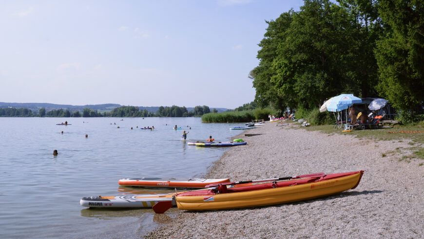 Am Badestrand des Sees baden mehrere Personen