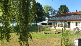 Außenansicht des Restaurants zum kleinen Fährhaus am See. Vor dem Restaurant ist ein kleiner Spielplatz.