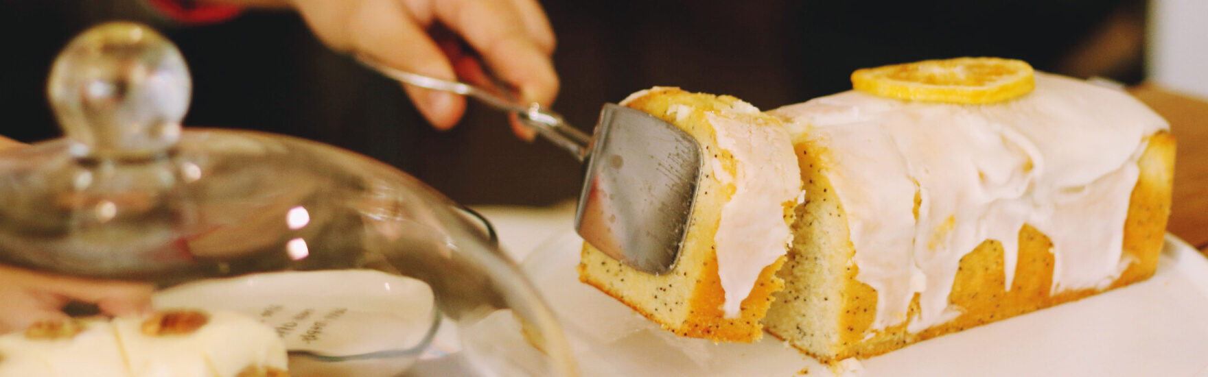 Ein Stück eines saftige Zitronenkuchens wird mit einer Zange angehoben