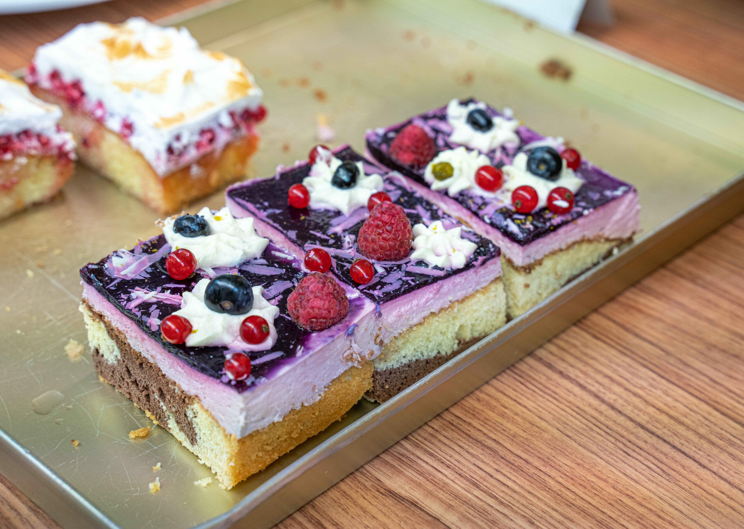 Mehrere Stücke eines saftigen Beerenkuchens mit Sahne