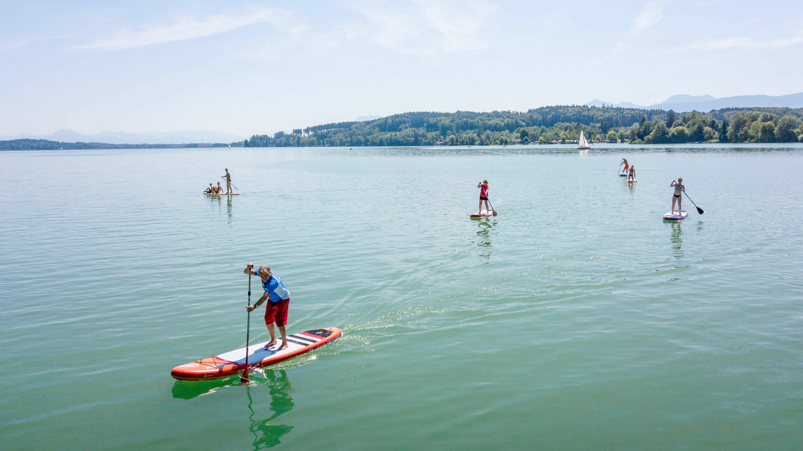 mehrere Stand-up-Paddler, die auf dem Waginger See fahren