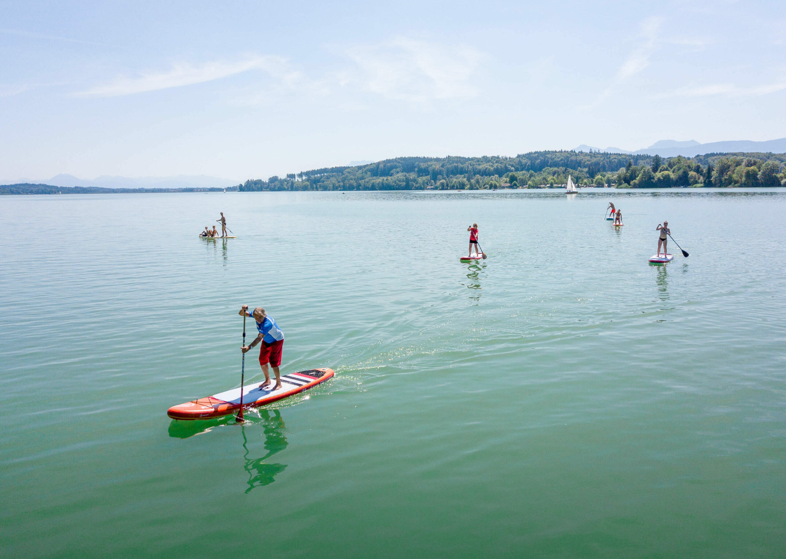 mehrere Stand-up-Paddler, die auf dem Waginger See fahren