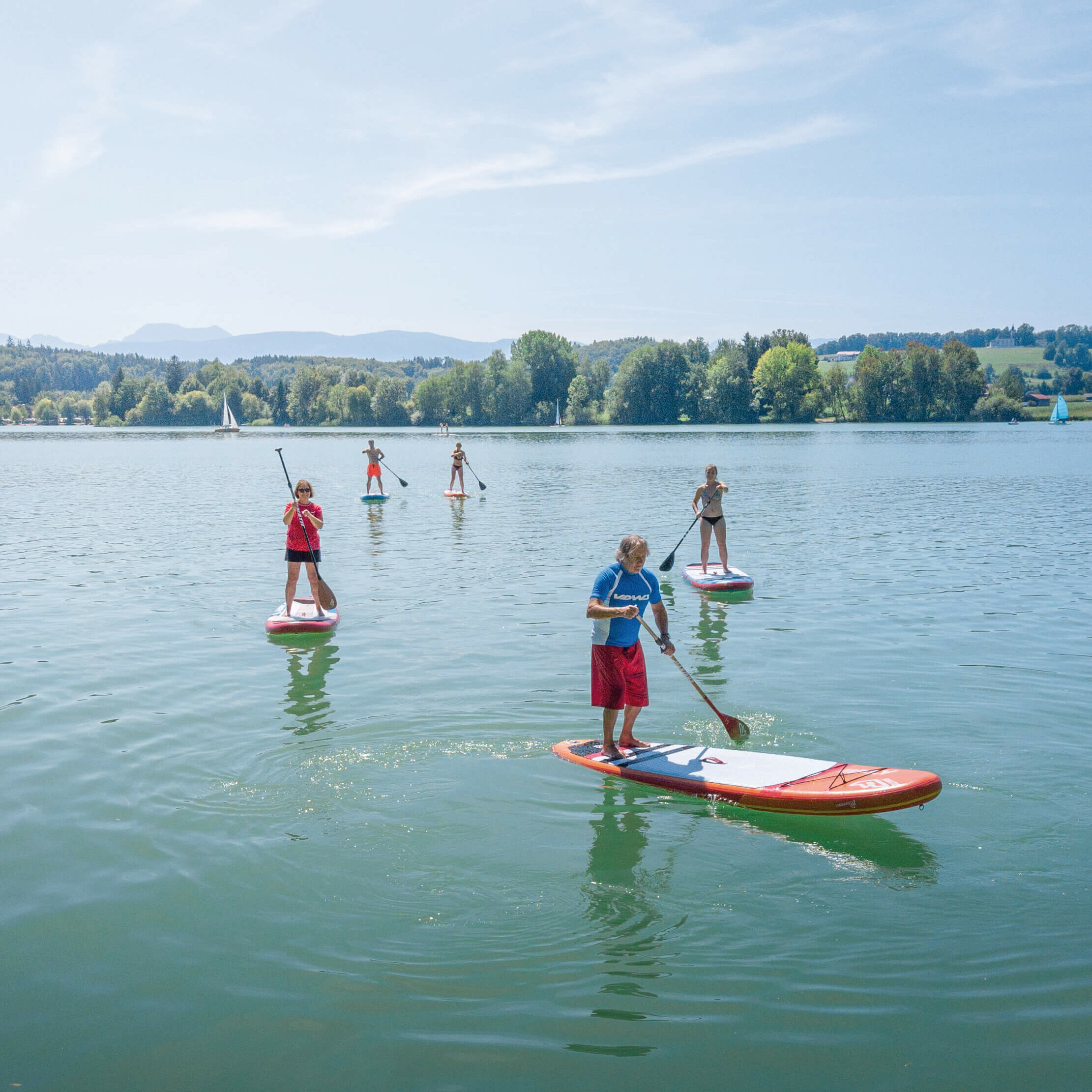 mehrere Stand-up-Paddler, die auf dem Waginger See fahren
