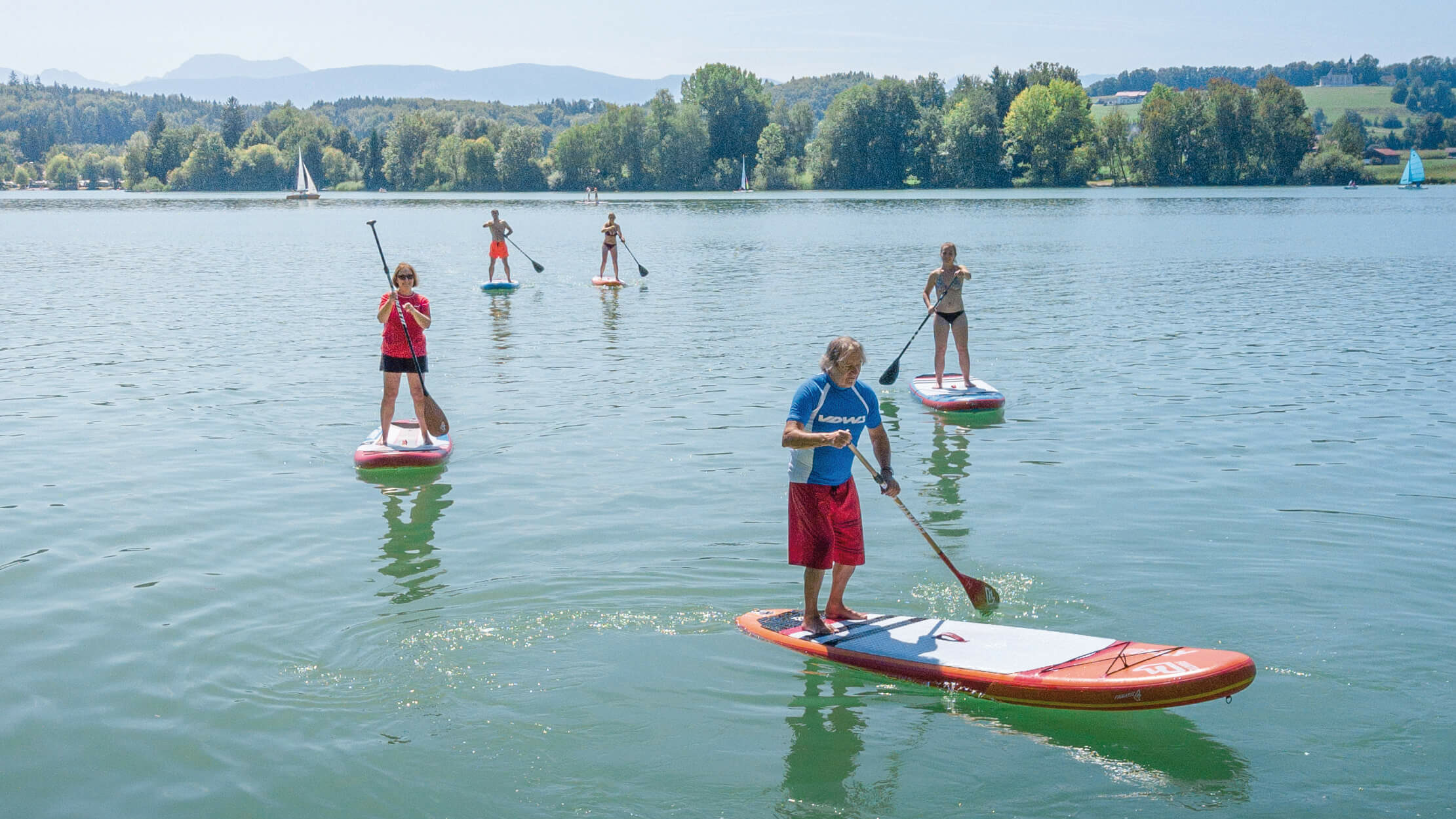 mehrere Stand-up-Paddler, die auf dem Waginger See fahren