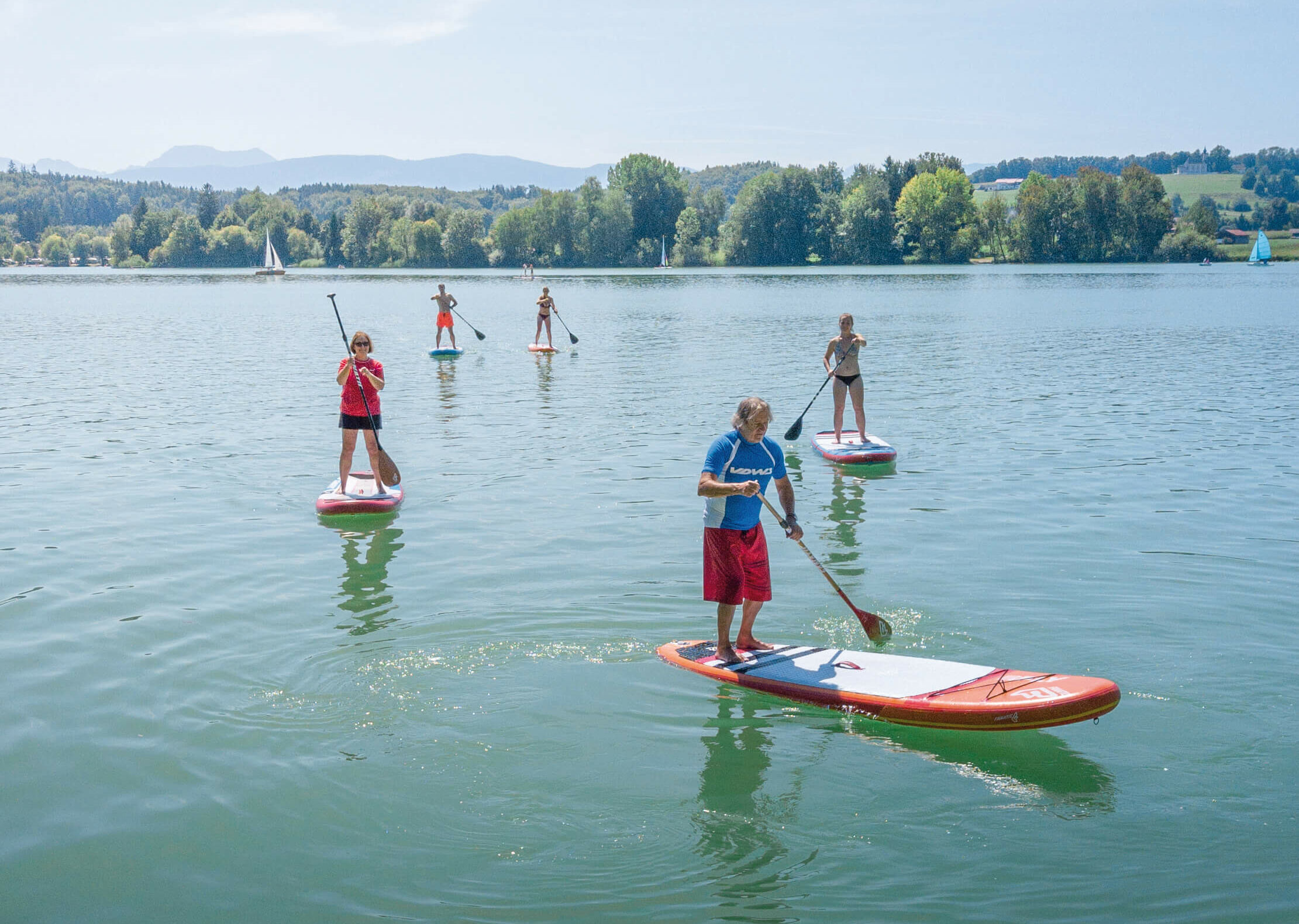 mehrere Stand-up-Paddler, die auf dem Waginger See fahren