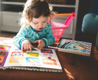 Ein kleines Kind liest ein großes buntes Buch