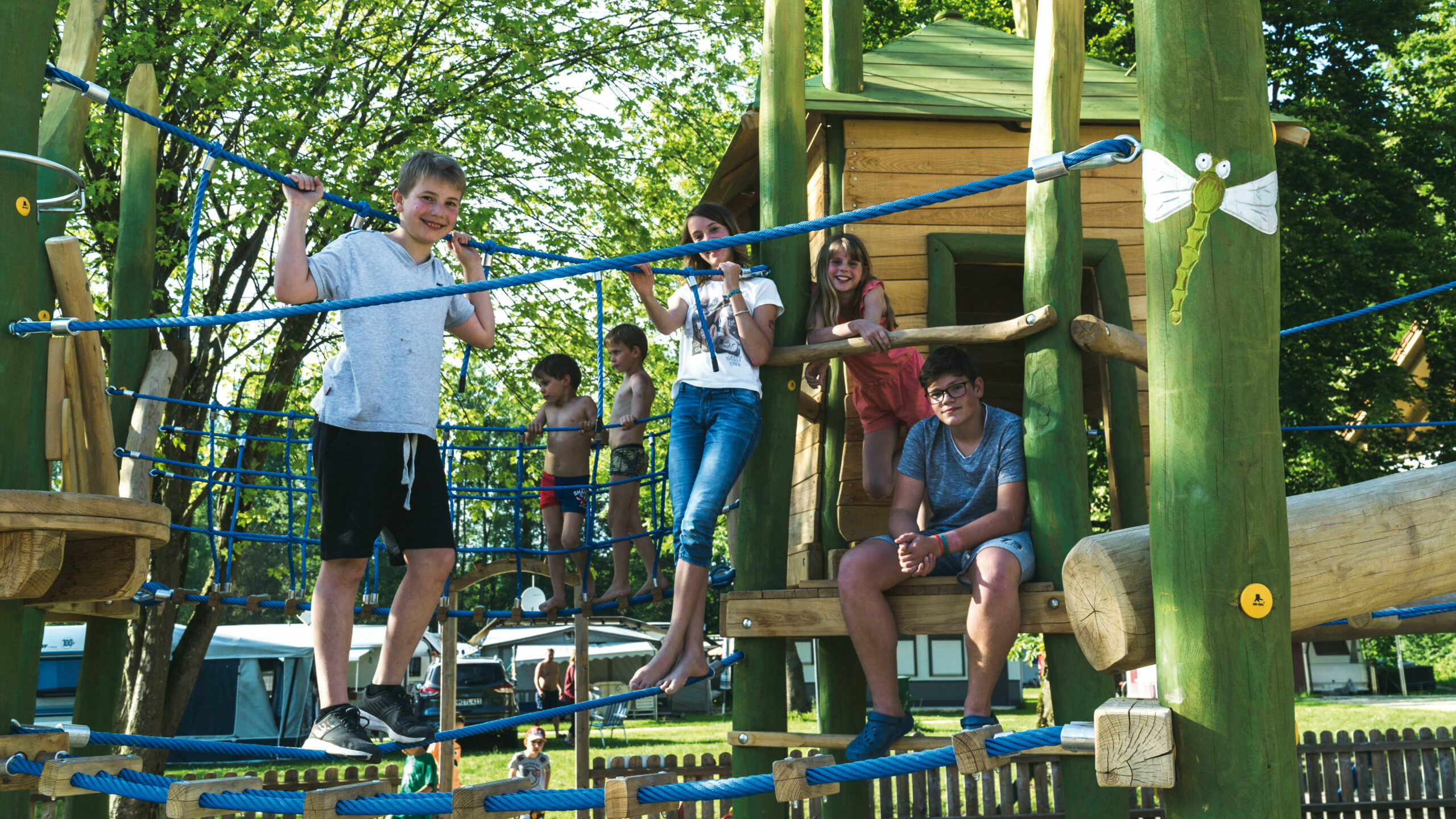 Kinder spielen auf einem Spielplatz mit vielen Hängebrücken und Klettermöglichkeiten