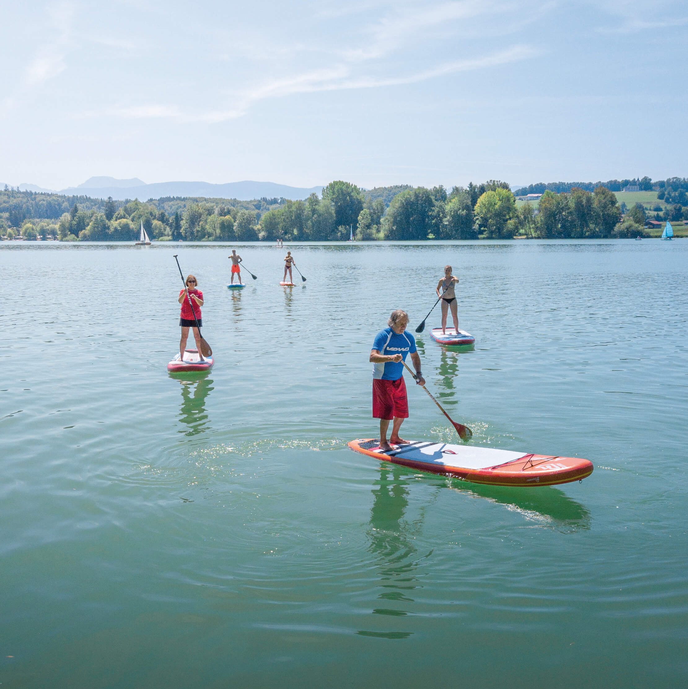 mehrere Stand-up-Paddler, die auf dem Waginger See fahren